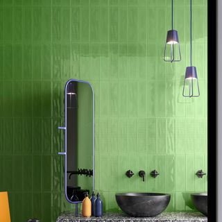bathroom with green rectangular tile wall black wash basin rectangular mirror and lamps