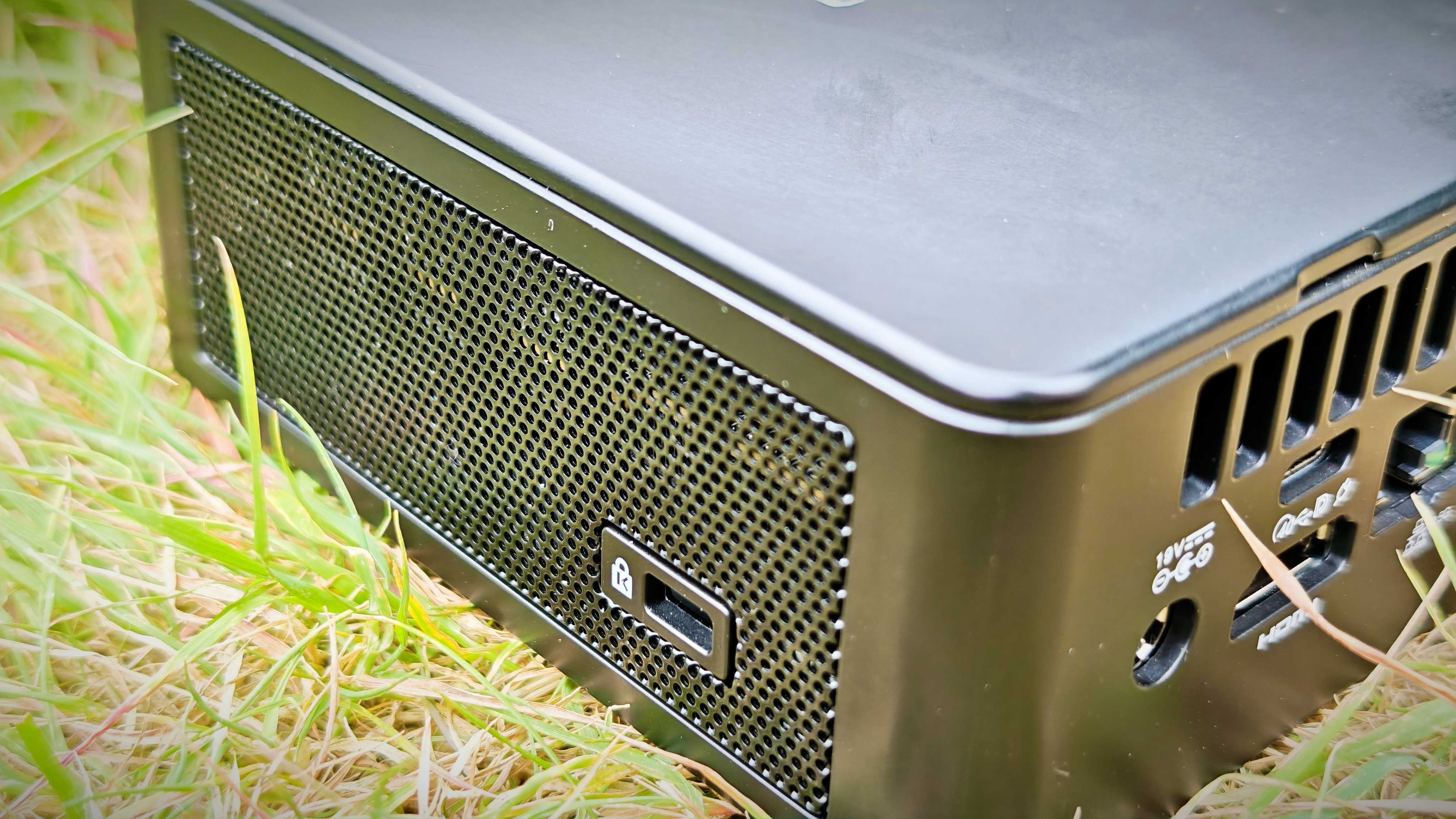 A black Geekom IT15 mini PC sitting in a grassy field