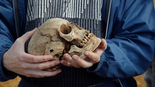 A close-up of a person holding a skull in their hands.