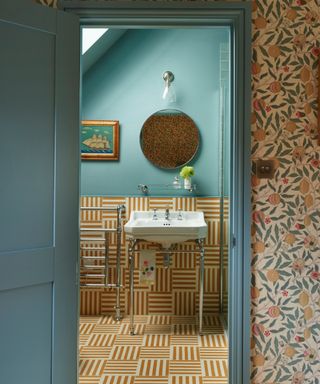 small bathroom flooring ideas, teal bathroom with yellow and white striped floor tiles that go halfway up the wall, round mirror, view of wallpaper outside bathroom