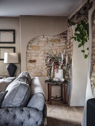 exposed stone wall section in cottage living room with festive flower display