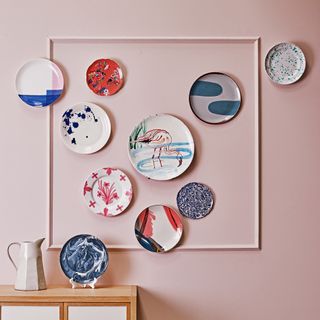 Display of patterned plates on pink wall
