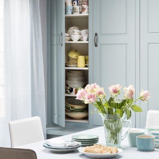 blue built-in cupboards in kitchen with white table and chairs