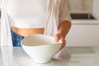 A woman skipping a meal with an empty bowl