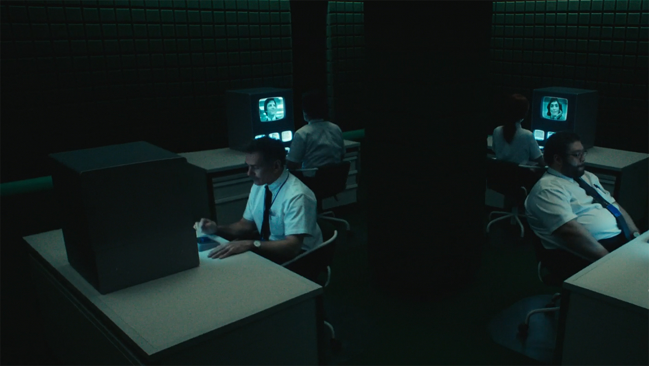 Four people sitting at a desk watching a computer monitor in Severance season 2