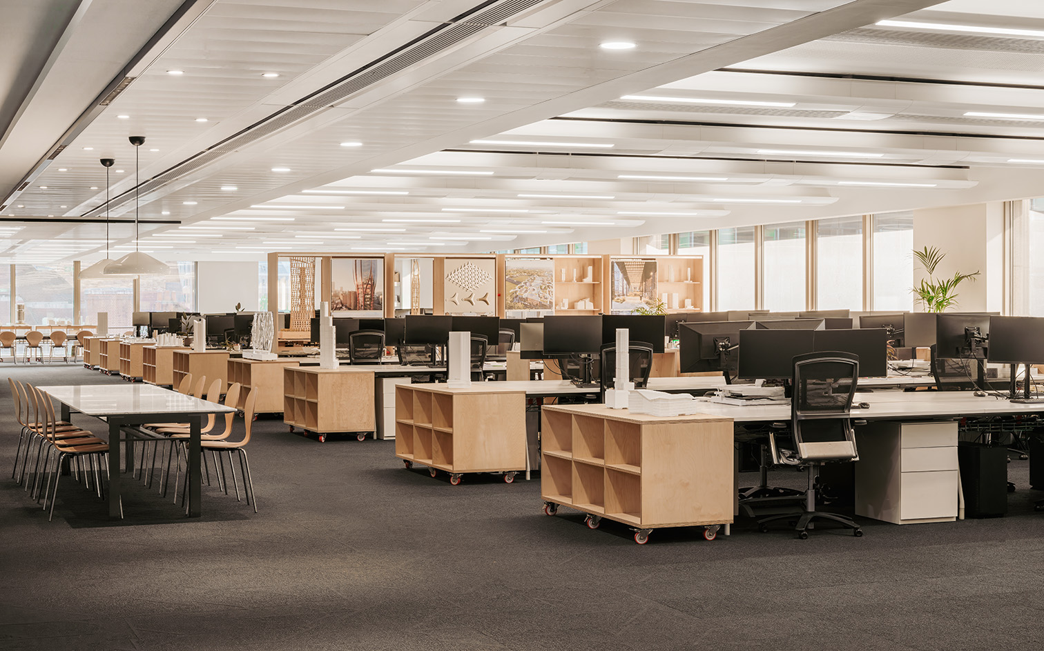 PLP Architecture&#039;s circular office design in neutral colours and soft light, showing empty workspace and timber seating and desks