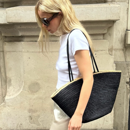 Photo of influencer wearing a spring 2026 outfit with satin pants, featuring white t-shirt, black raffia tote bag, and ivory satin pants.