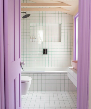 A crisp white bathroom with lilac door accenting