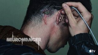 a person holds a wire with a male jack on the end of it up to their head, where a female plug can be seen surgically embedded into their skull behind their ear