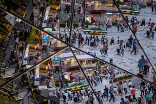 People are reflected in a mirror at an intersection in Harajuku Tokyo