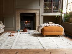 How to clean a wool rug – Living room with large rug, footstool and fireplace