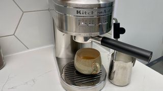 Bästa kaffemaskin: En espressomaskin står på en köksbänk, redo att brygga en kopp i muggen som står nedanför.