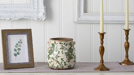 A wooden photo frame, a decorative vase, and dinner candles on a side table from QVC. 