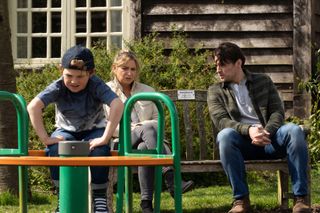 Moses plays on the roundabout in the playground as Charity Dingle and Mackenzie Boyd talk on the bench