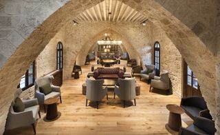 Lounge, seating area, old fashioned couches, wooden flooring with old exposed stone walls with exposed roofing