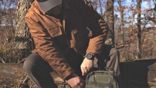 Man fastening backpack wearing Garmin Instinct 2X watch