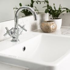 Silver tap over white sink in bathroom
