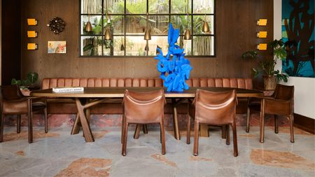A dining room with brown furniture, brown walls and Palladiana flooring
