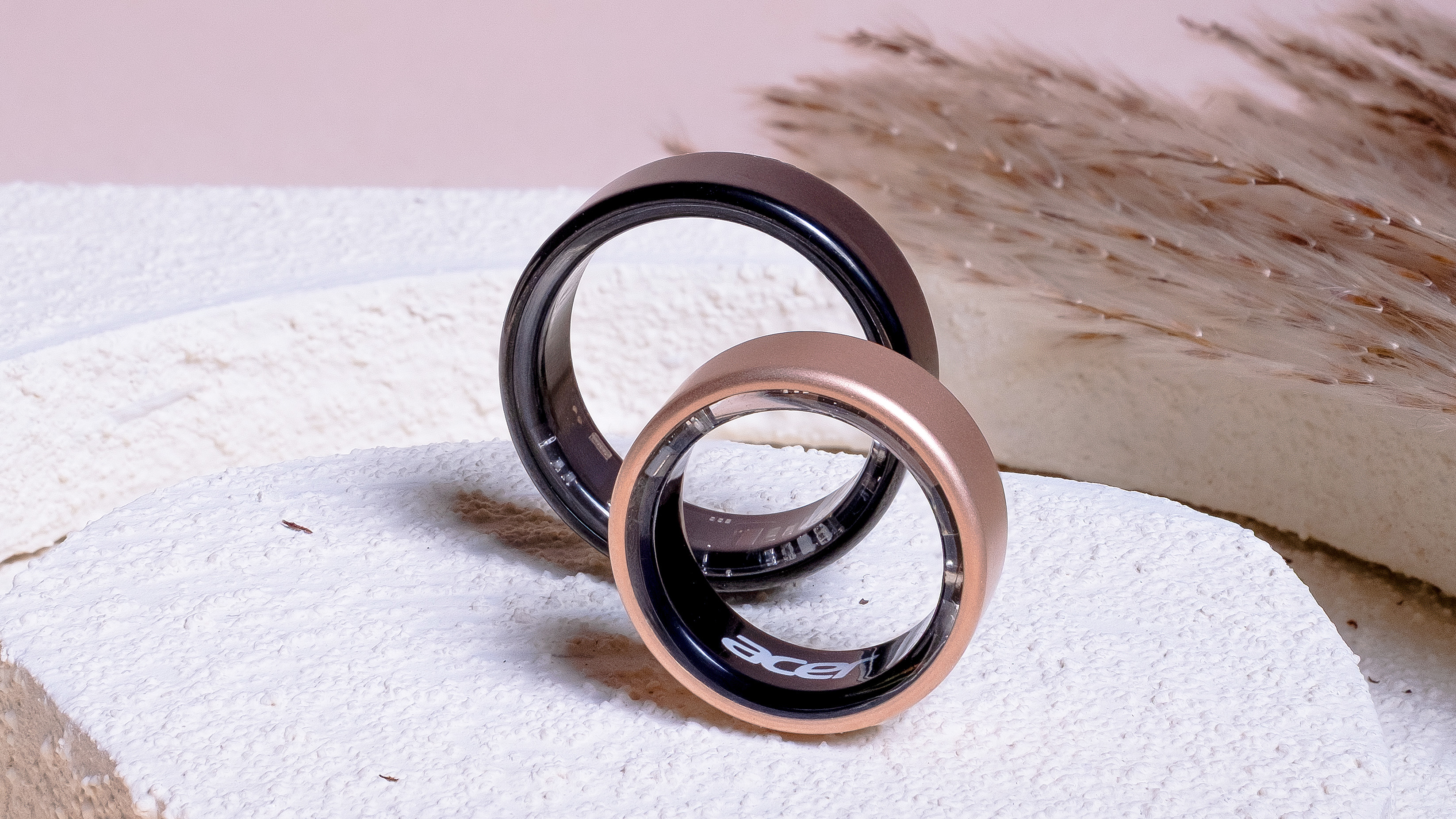 Close-up of two Acer FreeSense smart rings sitting on a stone surface in both black and rose gold