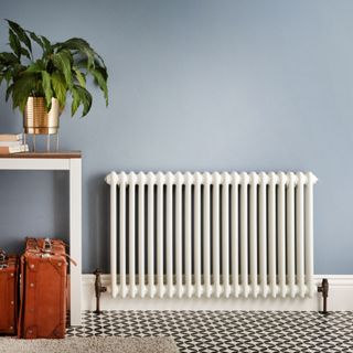 White radiator in front of blue wall next to console unit