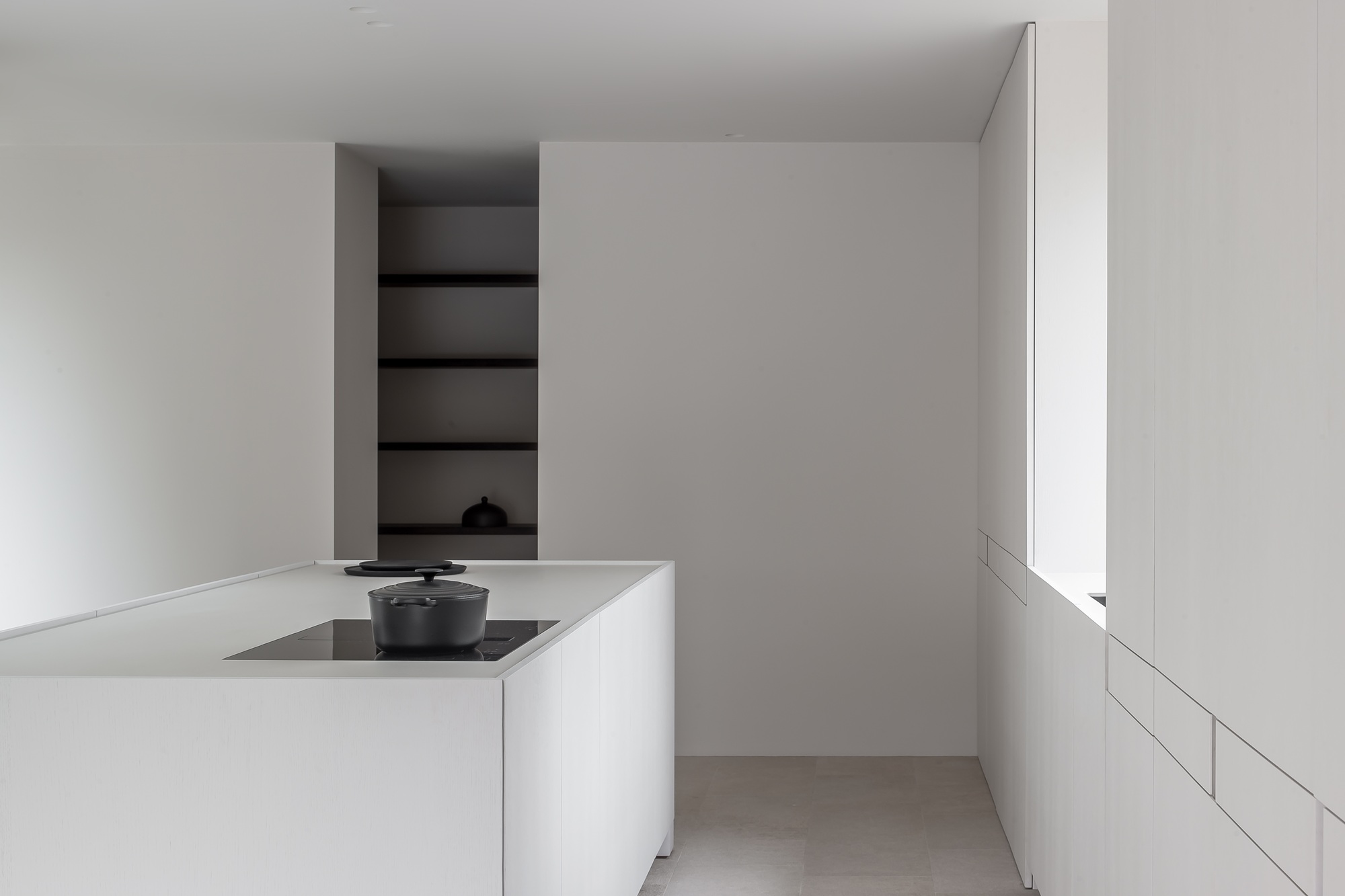 a white minimalist kitchen in an apartment with a stove on the white island