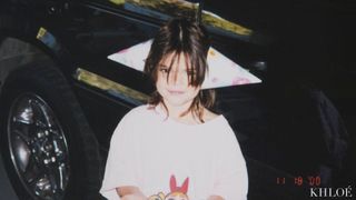 A young Kendall Jenner wearing a party hat on either side of her head.