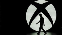 The silhouette of Ralph Fulton, design director for Forza Horizon at Playground Games, is seen walking past the Microsoft Corp. Xbox One logo uring a media event ahead of the E3 Electronic Entertainment Expo in Los Angeles, California, U.S., on Monday, June 9, 2014. Microsoft Corp. and Sony Corp. are gearing up for the next phase of competition between their dueling video-game consoles, highlighting exclusive titles that will be on sale for the year-end holiday season. Photographer: Patrick T. Fallon/Bloomberg via Getty Images 