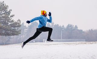 a photo of a male runner warming up outside in the snow