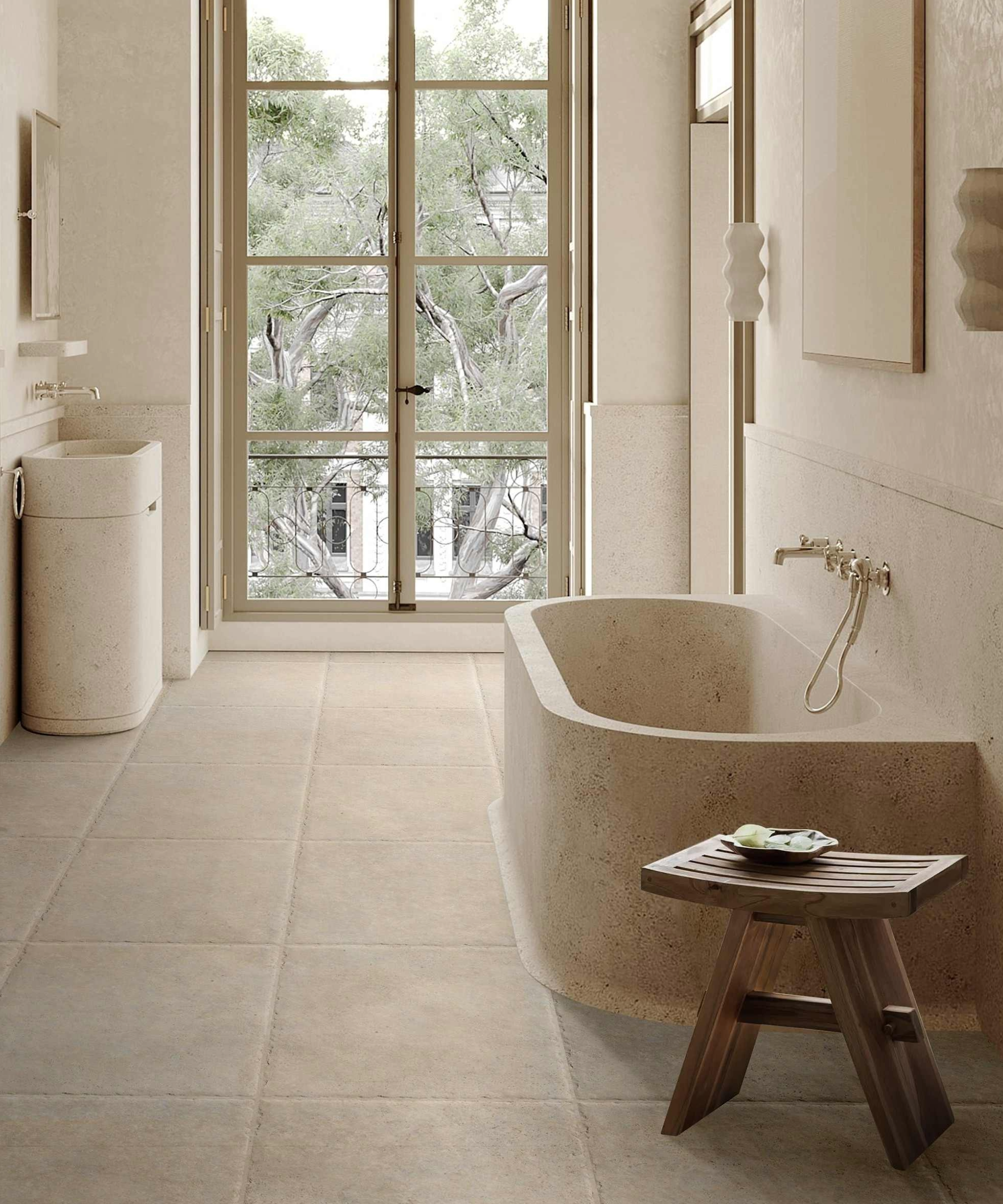 Neutral bathroom with stone bath and sink, with large windowed door at the end of the room