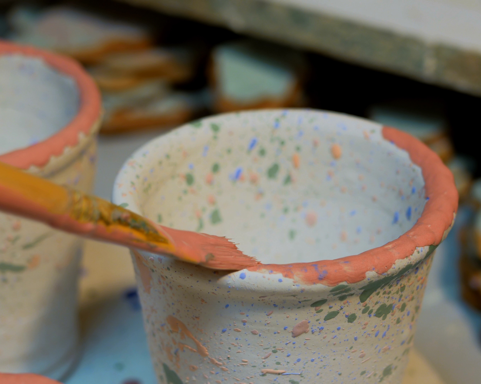 paint being applied to the rim of a plant pot
