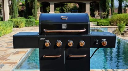 A Kenmore 4 Burner Gas Grill in front of a pool