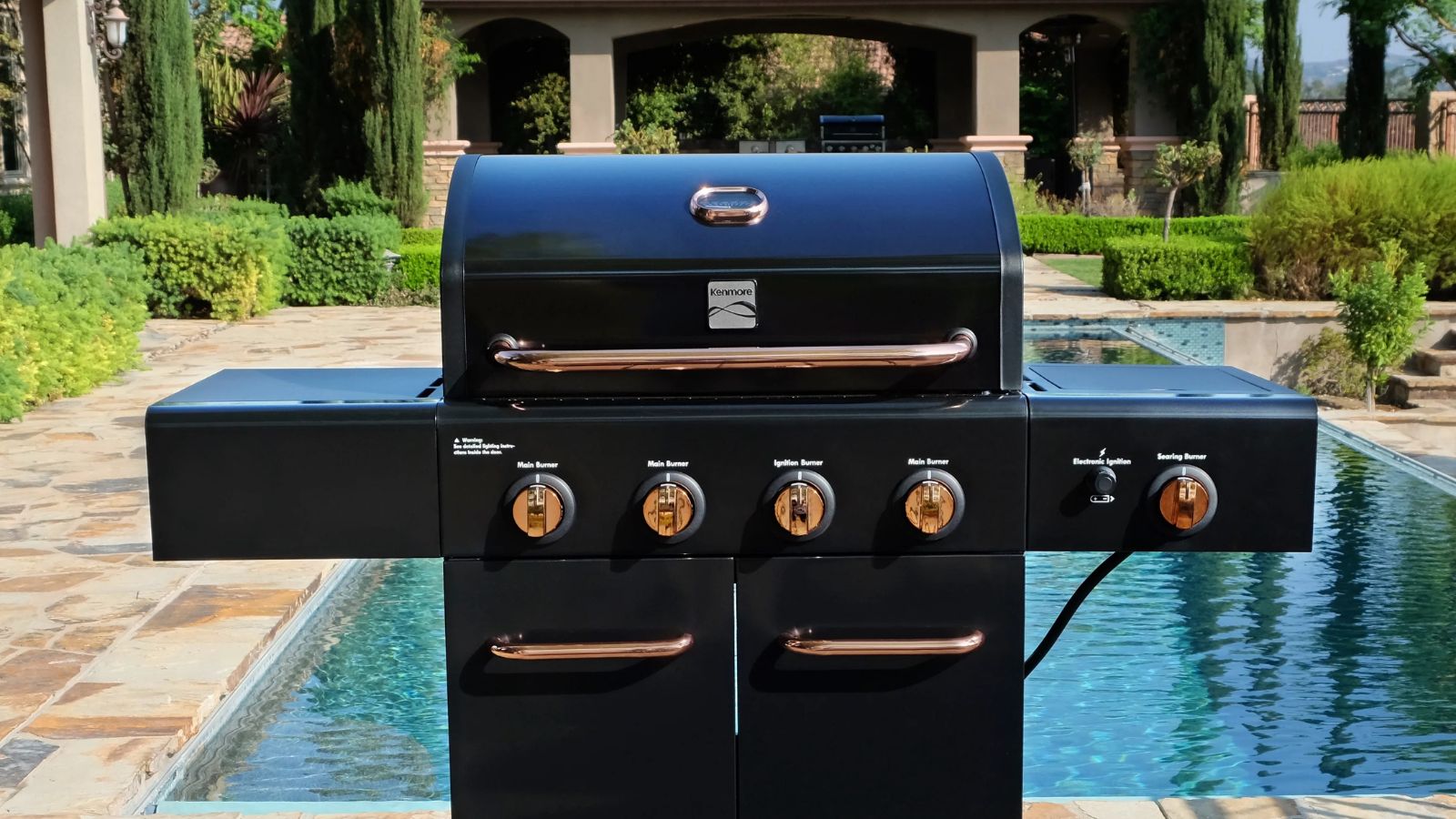  A Kenmore 4 Burner Gas Grill in front of a pool