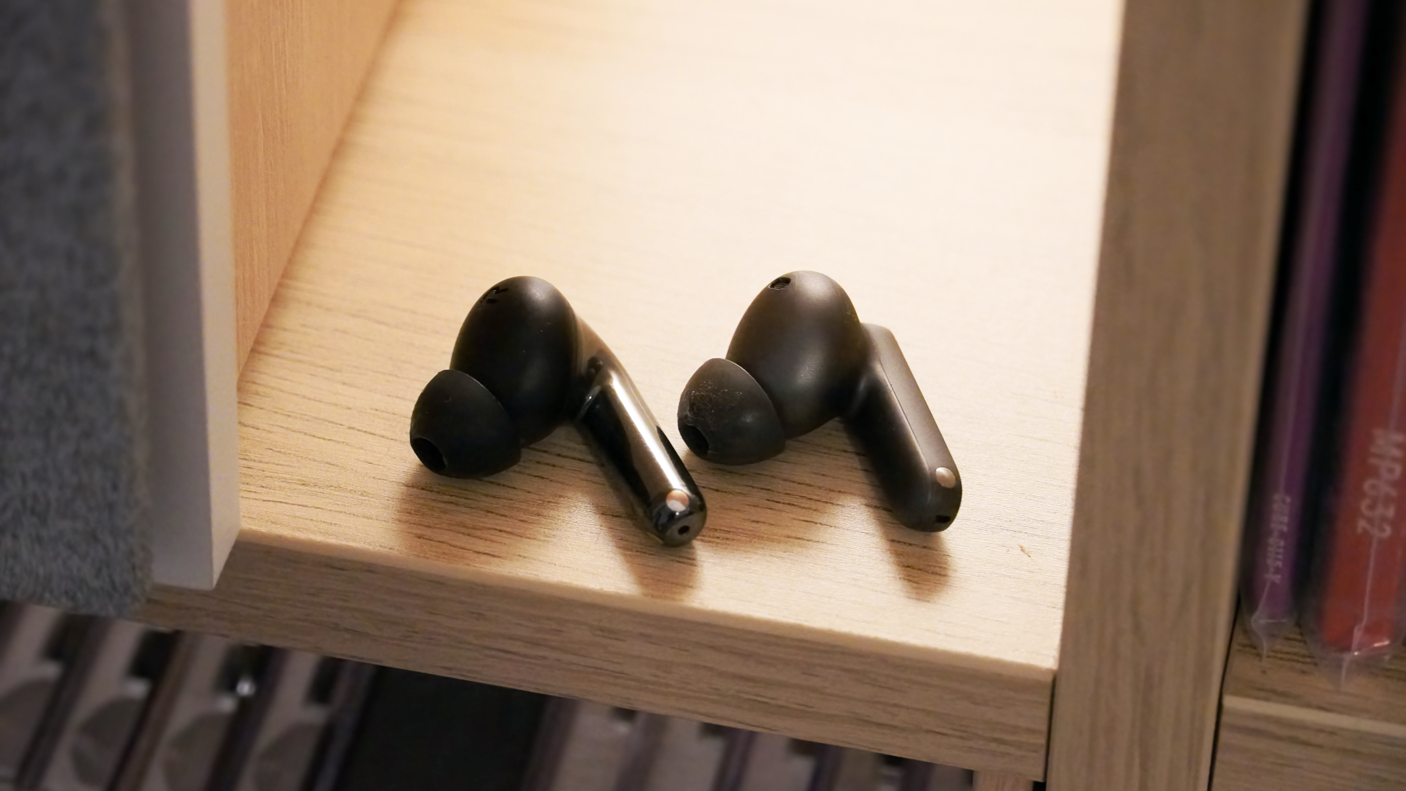 The OnePlus Buds 4 and the OnePlus Buds Pro 3 left earbuds on a shelf.