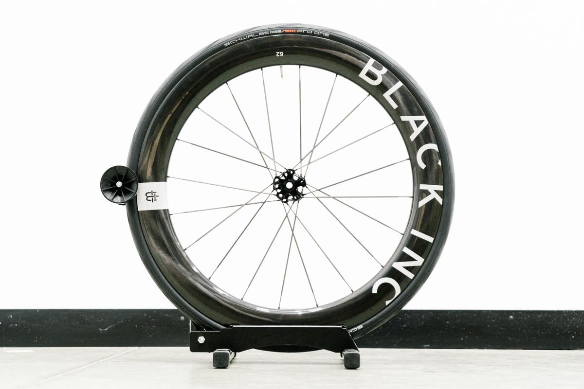 An aero road wheel stands against a white wall