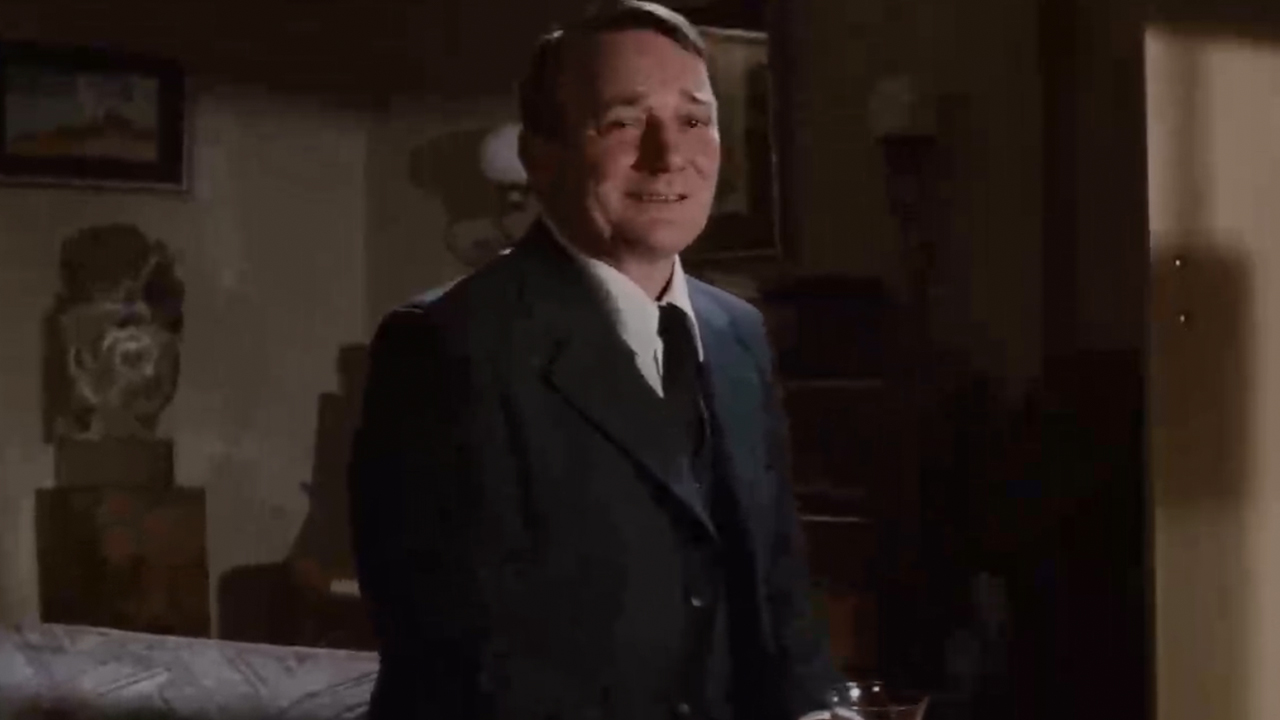 Denholm Elliott smiling, wearing a suit in Raiders of the Lost Ark