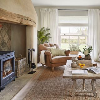 country living room with large rug, wooden coffee table, brown armchair and log burner