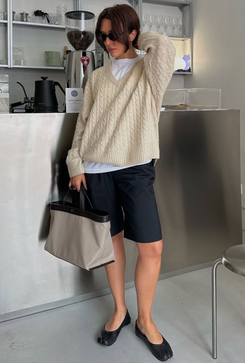 @deborabrosa wears a cream cable knit jumper, white t-shirt, navy Bermuda shorts, black ballet flats and grey canvas tote and sunglasses