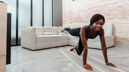 best resistance bands: Pictured here, a young athletic women exercising in a living room using stretch bands