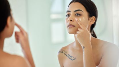 woman applying one of the best sunscreen for acne-prone skin - getty images 1389859311