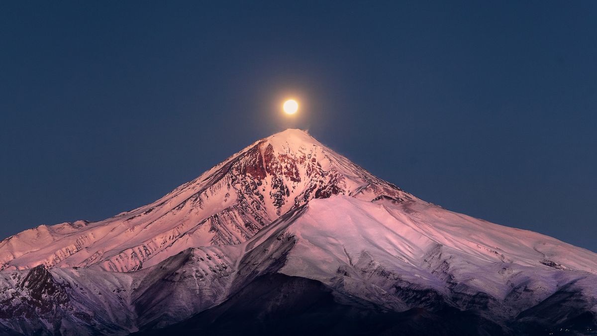 The full moon shines over snow-capped mountains in Mazandaran Province, Iran.