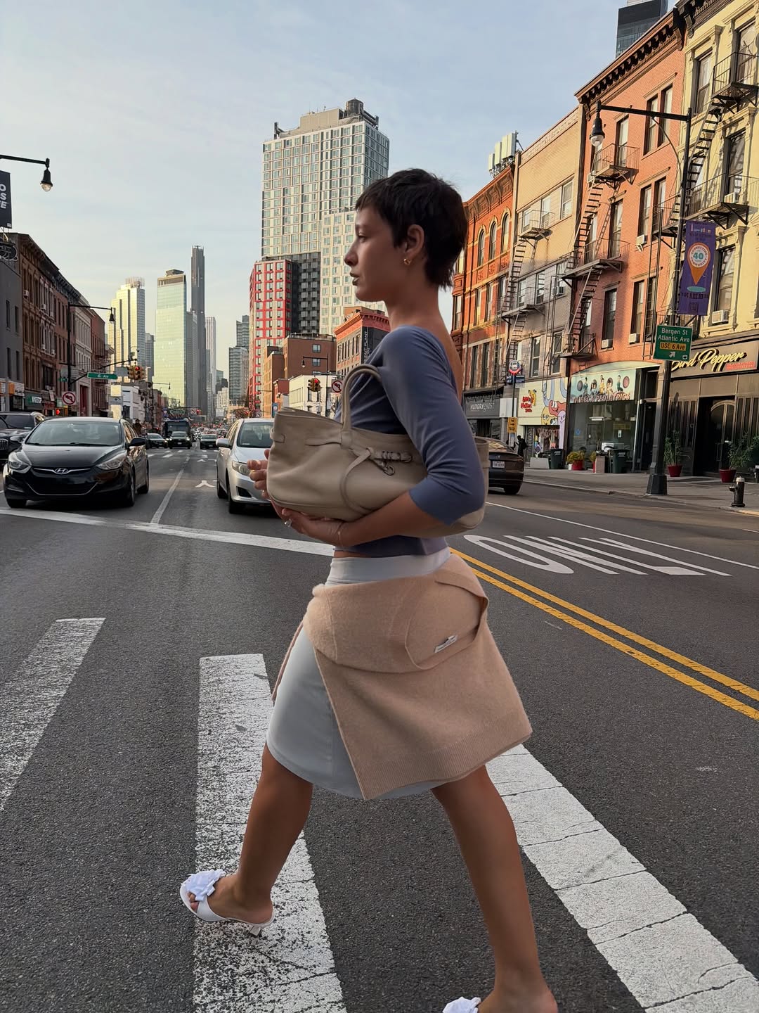 A woman wearing sweater around waist, one of the biggest 2026 spring to summer transitional trends.