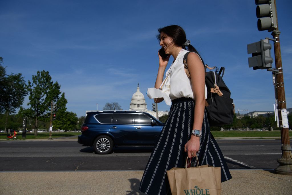 A woman not wearing a face mask speaks on the phone as she walks past the US Capitol in Washington, DC, on April 27, 2021