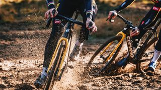 Wout van Aert and Marianne Vos riding a Cervélo R5-CX cyclo-cross bike in Jumbo-Visma's yellow and black colours through sand