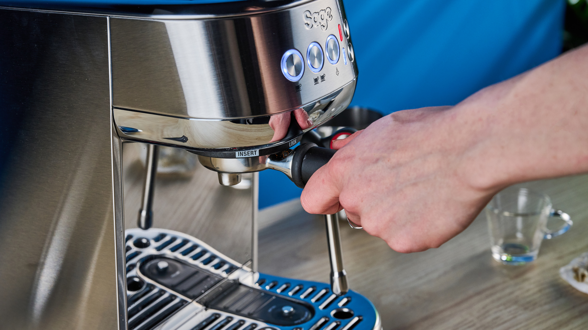 the breville bambino plus / sage bambino plus in stainless steel silver photographed against a blue background shown with its accessories including milk jug, tamper, portafilter, and shown in use extracting espresso