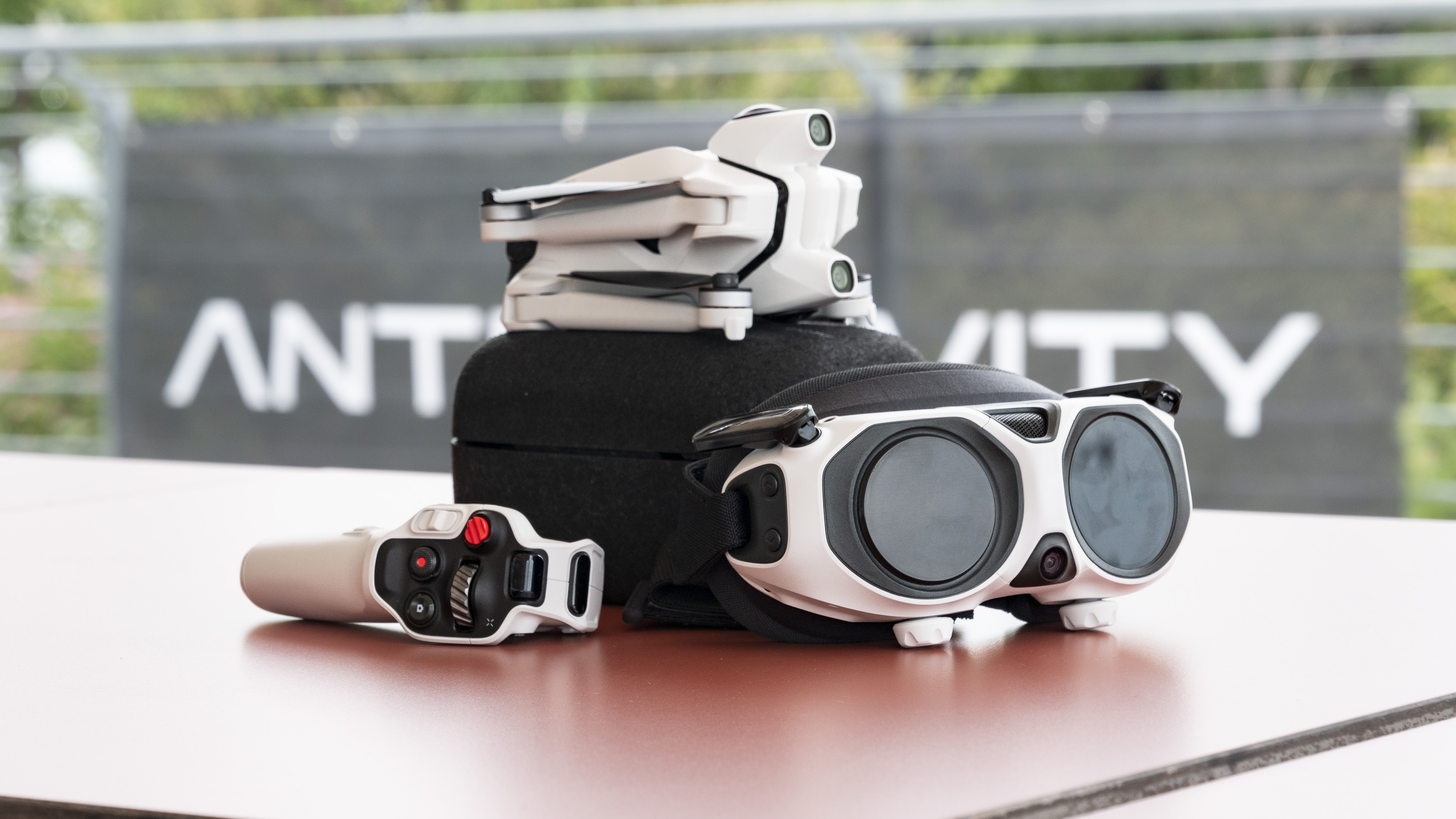 Antigravity A1 drone by Insta360 alongside its headset and controller, on a red table