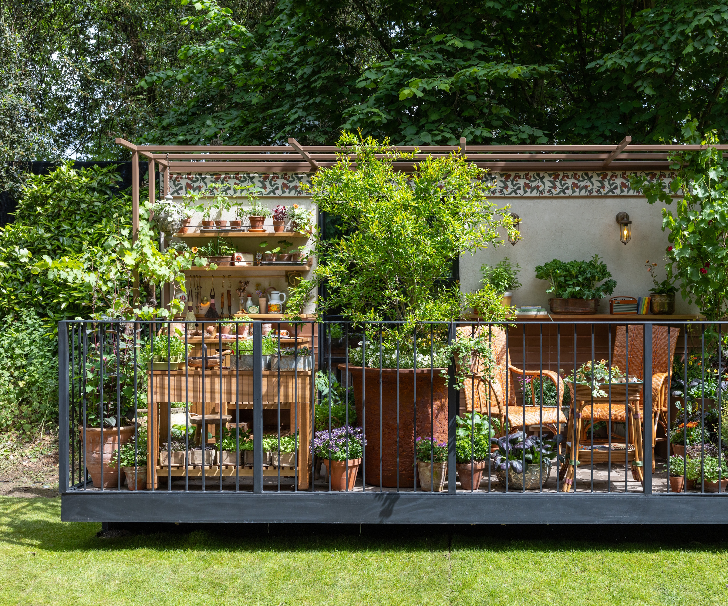 Balcony garden with wicker chairs, retro styling and large shrubs in brown pots