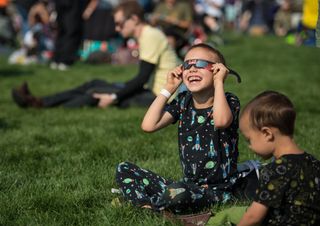 A boy watches the total solar eclipse through protective glasses in Madras, Oregon, on Aug. 21, 2017.