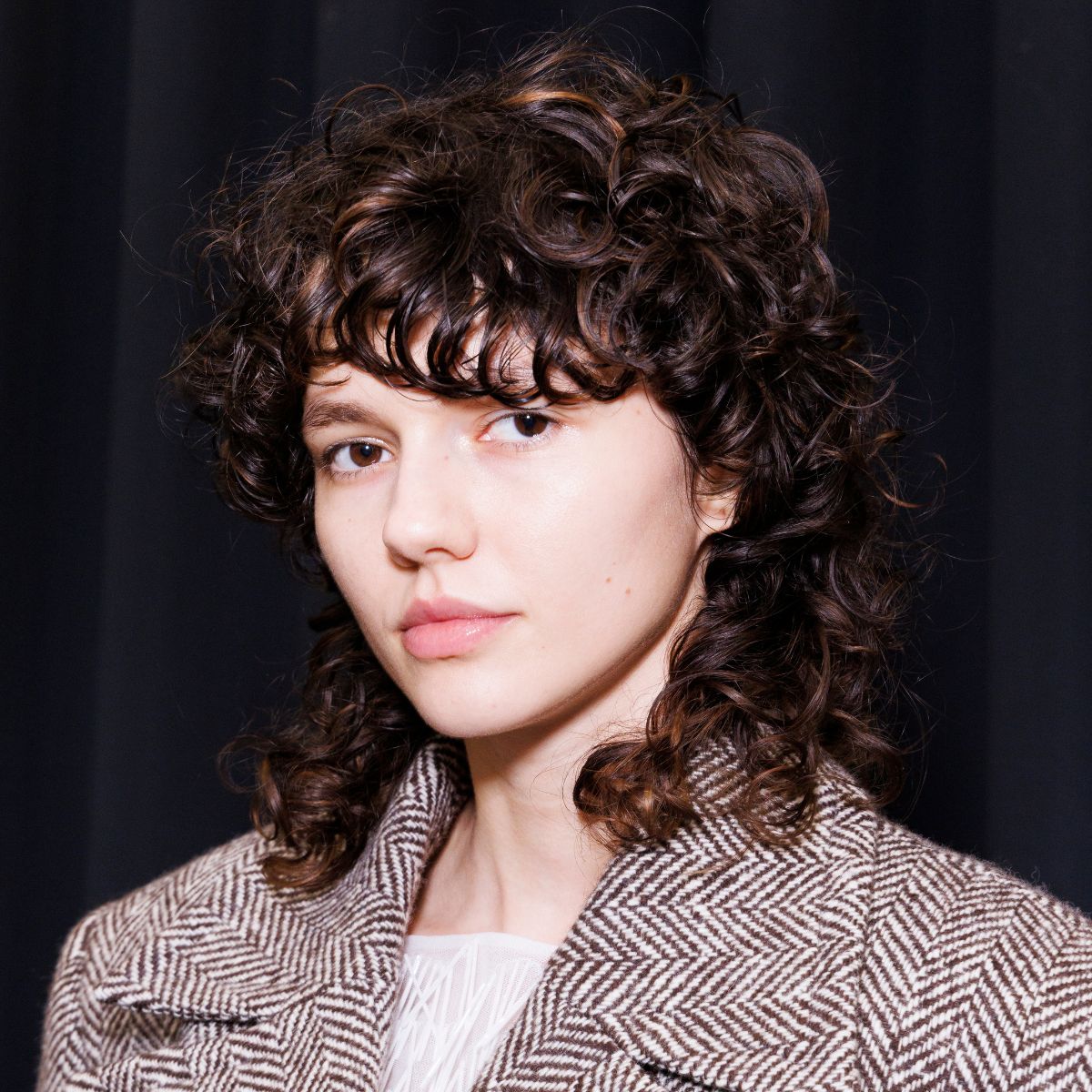 model with brown curly wolf cut