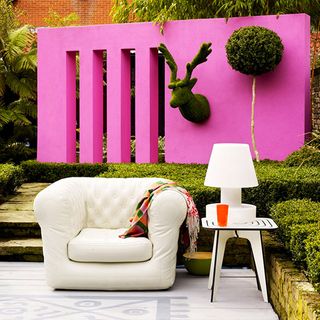 garden area with pink wall and white sofa with table and lamp
