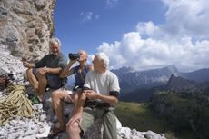 Italy, Tyrol, three senior hikers sitting on mountain edge
